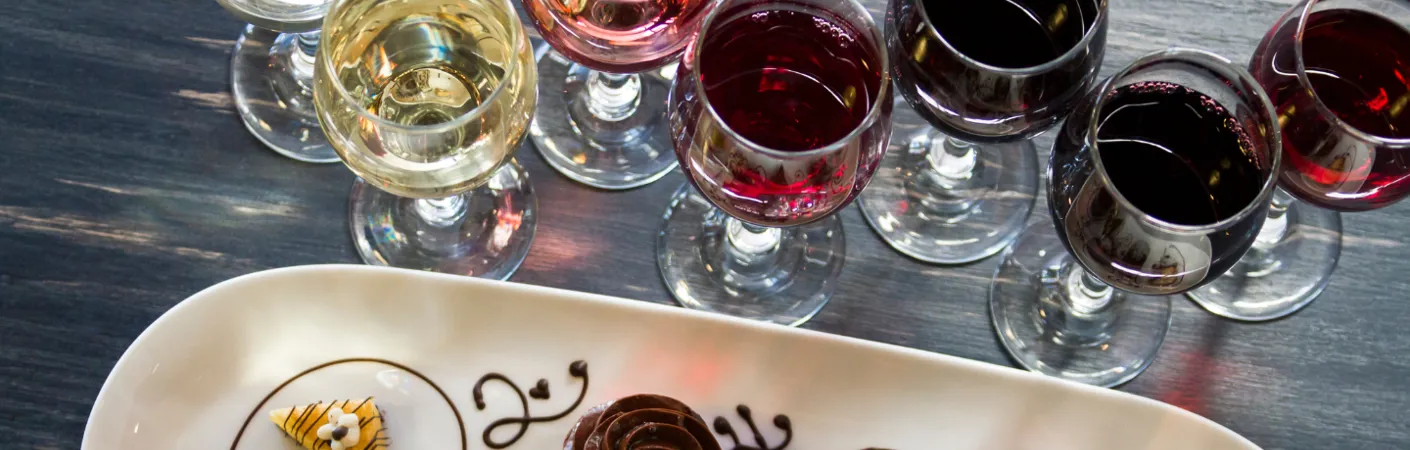 Flere glas dessertvin står på et bord ved siden af desserter