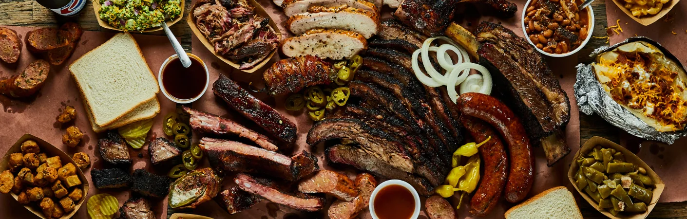 Udvalg af grillmad med forskellige slags grillet kød, pølser, spareribs og tilbehør, vist som stemningsbillede til valg af vin til grillmad