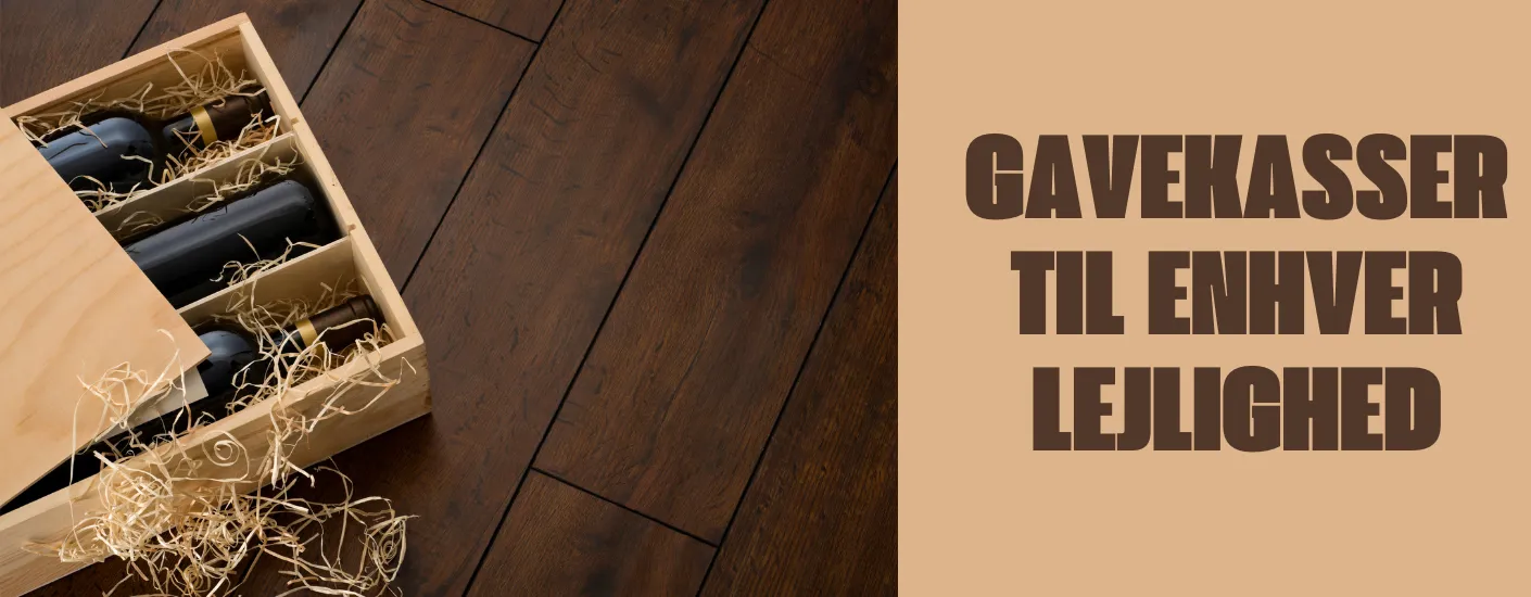 Åben trækasse med flere flasker lagt i træuld på et mørkt trægulv, ledsaget af teksten “Gavekasser til enhver lejlighed”